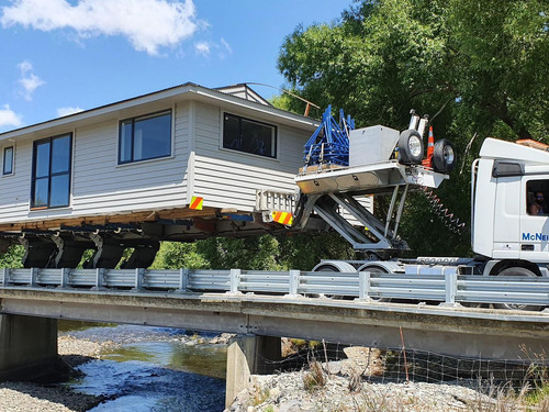 A transportable home being transported in the South Island across a bridge