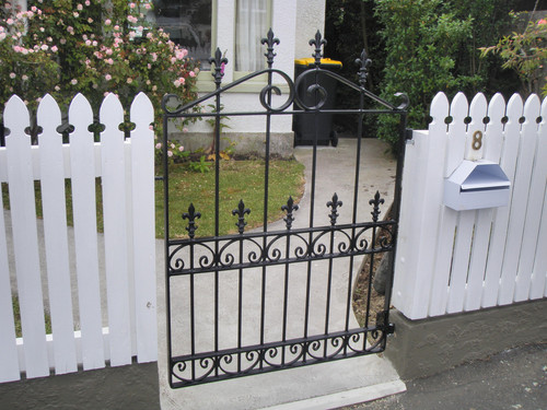Decorative wrought iron gate with white picket fence