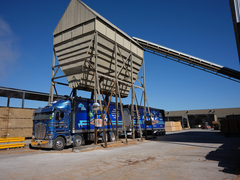 The hopper is loading up the walking floor truck with dry animal bedding