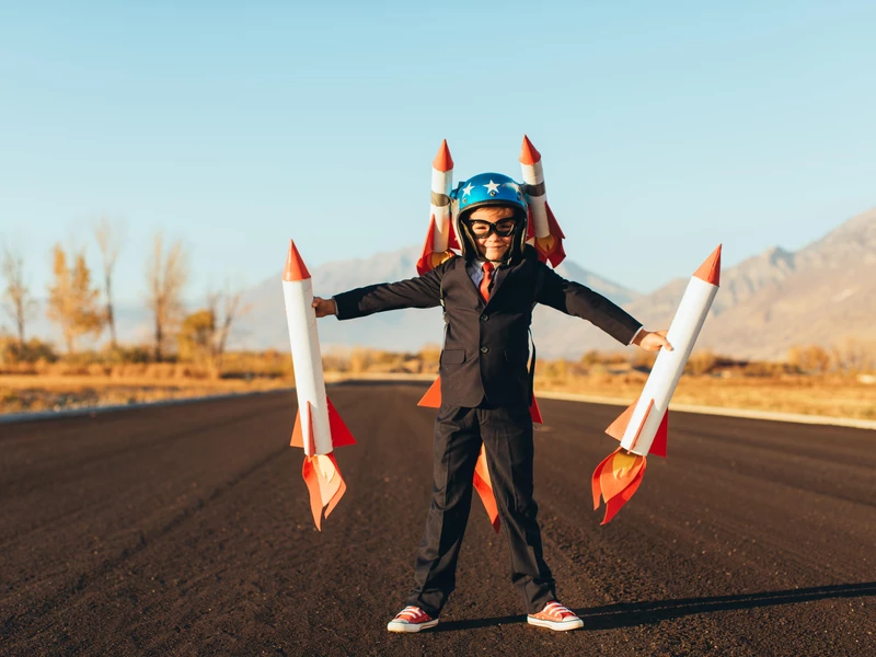 Boy holding rockets shows the choice between custom websites and template websites Boy holding rockets shows the choice between custom websites and template websites