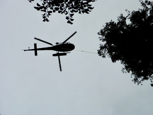 Helicopter lowering section of pipe into Deep Cove