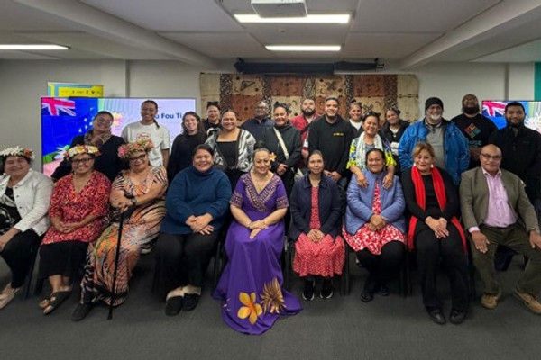 The image shows about 20 people formally posed for a picture.  The front row are seated and there are two rows behind standing.  