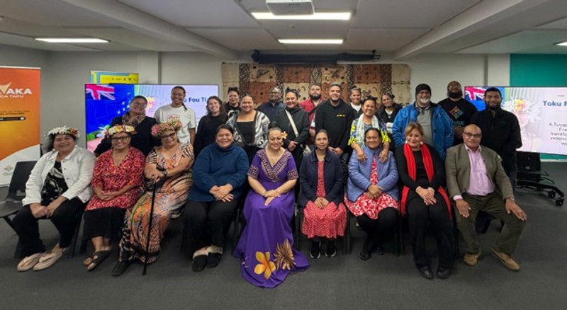 The image shows about 20 people formally posed for a picture.  The front row are seated and there are two rows behind standing.  