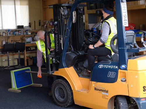 Operating a forklift to pick up a gravestone