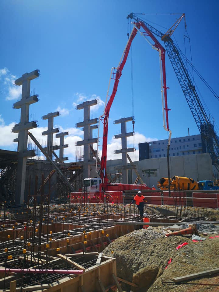 Concrete pump truck, concrete building, construction site. 